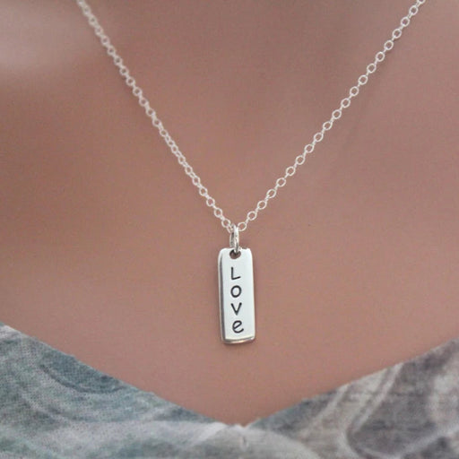 Silver necklace with 'LOVE' pendant on a neutral background