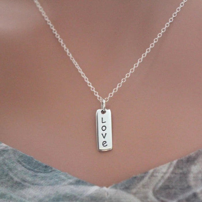 Silver necklace with 'LOVE' pendant on a neutral background
