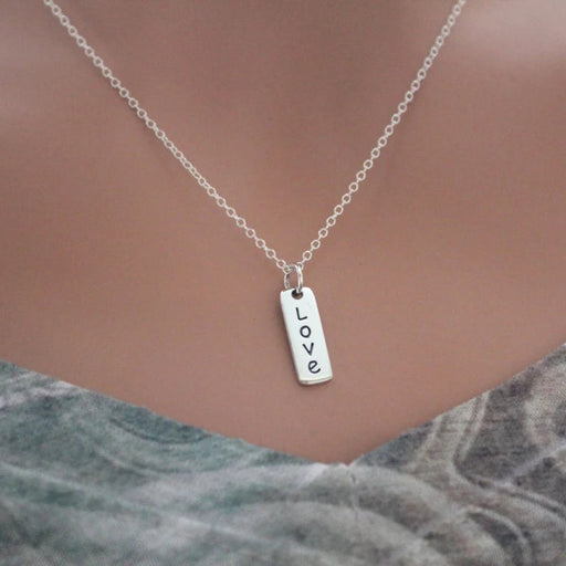 Silver necklace with 'LOVE' pendant on a mannequin