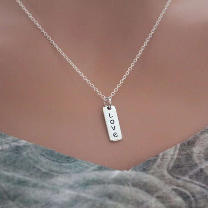 Silver necklace with 'LOVE' pendant on a mannequin