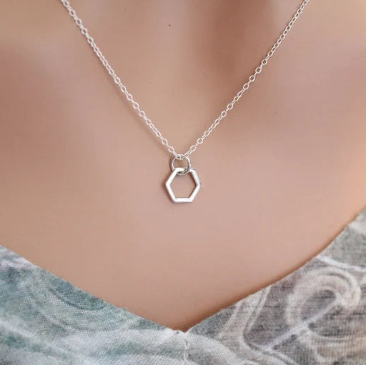 Silver hexagonal pendant necklace on a mannequin with a marble background
