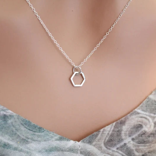 Silver hexagonal pendant necklace on a mannequin with a marble background