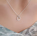 Silver hexagonal pendant necklace on a mannequin with a marble background