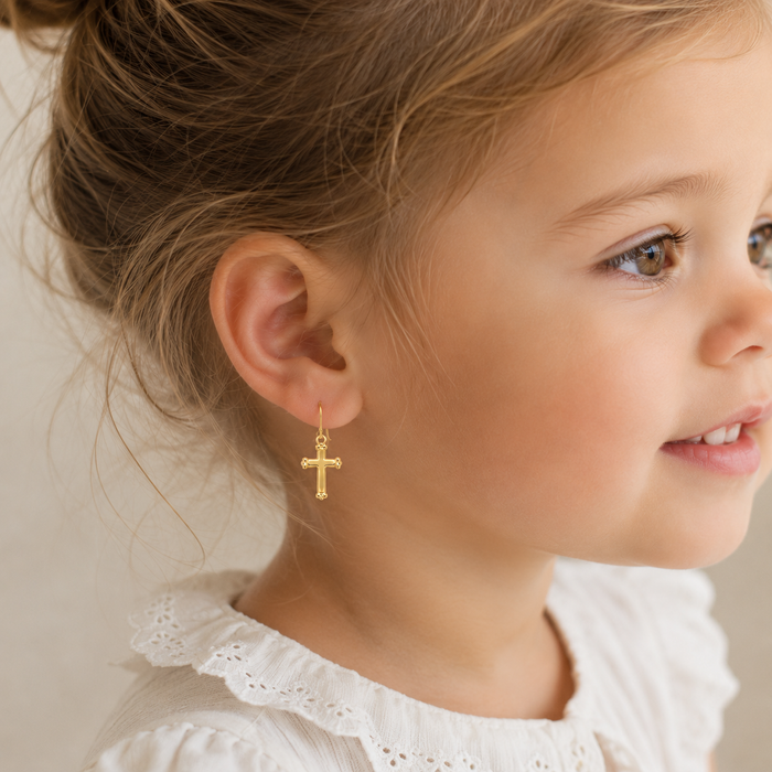 Close-up of a young girl wearing a gold cross earring.