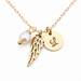Gold chain necklace with angel wing charm, round initial pendant engraved with 'L', and a white pearl bead charm on a white background.