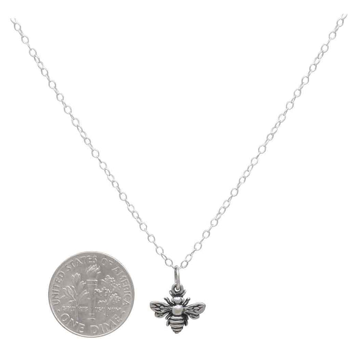 close up of a sterling silver bumble necklace pendant next to a USD dime