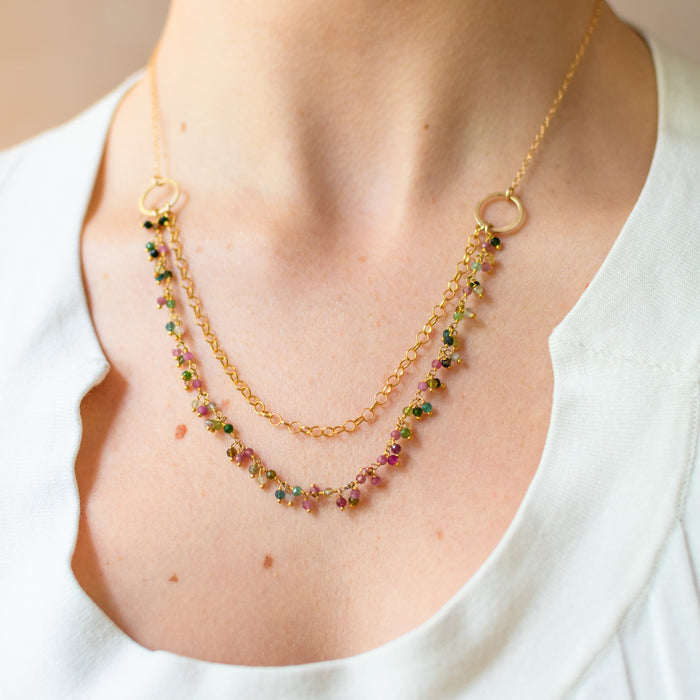 Necklace with gemstones worn by a person in a white top