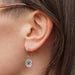 a compass charm sterling silver earring hangs from the ear of a model
