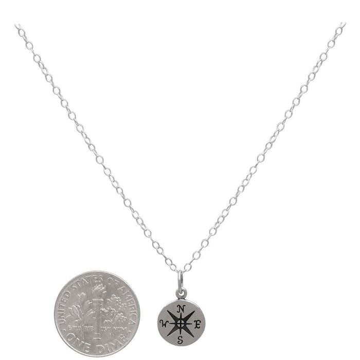 sterling silver compass necklace next to a USD dime to showcase size