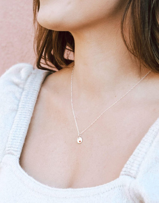 Model wearing dainty birthstone disc necklace with personalized charm on 18-inch chain.
