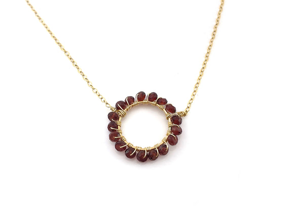 gold necklace with a circle of garnet beads wire wrapped