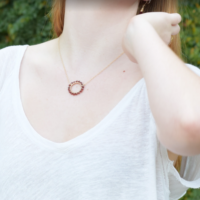 photo of a model in a white shirt displaying a handmade gold and garnet necklace