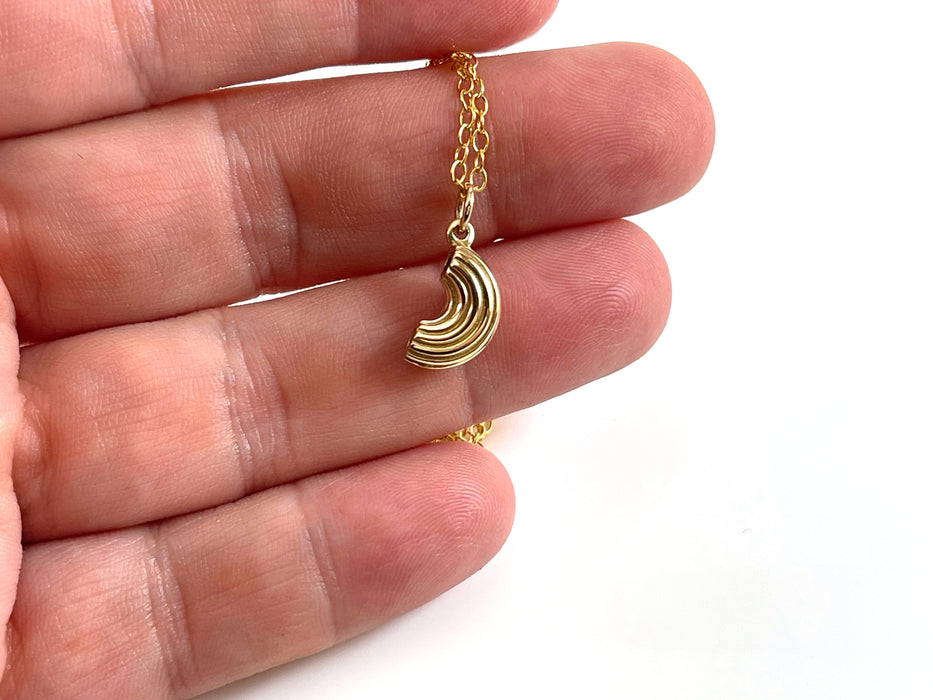 gold macaroni noodle charm necklace held in hand to showcase size