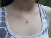 view of a models neck wearing a gold filled bumblebee necklace on a gold chain hanging just below her collarbones