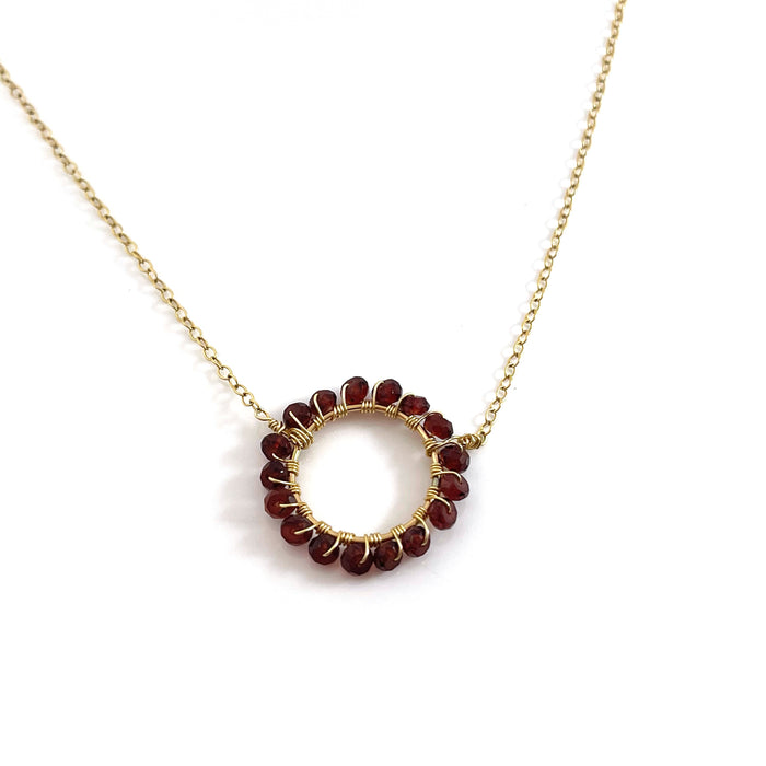 gold necklace with wire wrapped garnets in a circle shape
