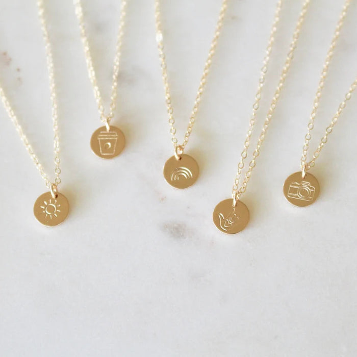 Gold necklaces with small round pendants on a light background