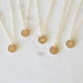 Gold necklaces with small round pendants on a light background