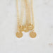 Gold necklaces with round pendants on a marble surface