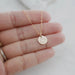 close up of a hand holding a gold filled texas state necklace to showcase size