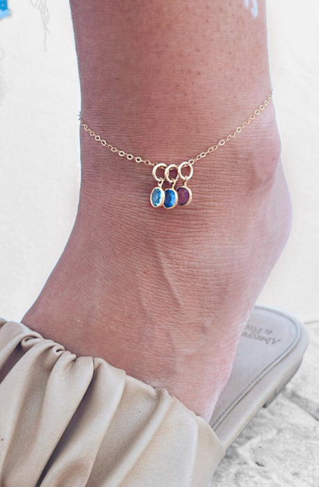 Custom anklet with two Swarovski birthstone charms in silver, worn casually with summer outfit.

