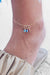 Custom anklet with two Swarovski birthstone charms in silver, worn casually with summer outfit.

