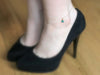 Close-up of Swarovski birthstone anklet in gold, worn with black heels.
