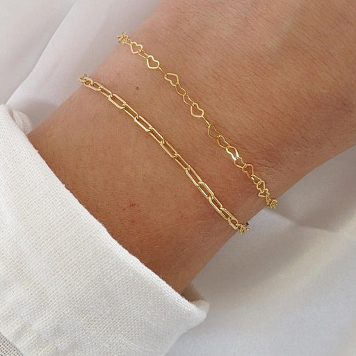 Gold bracelet on a wrist with a white shirt background