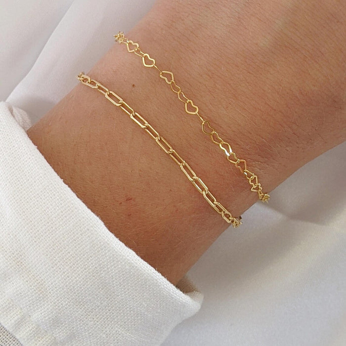 Gold bracelet on a wrist with a white shirt background