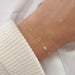 Gold bracelet with heart links on a wrist against a white background