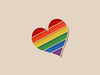 Rainbow heart-shaped pin on a beige background