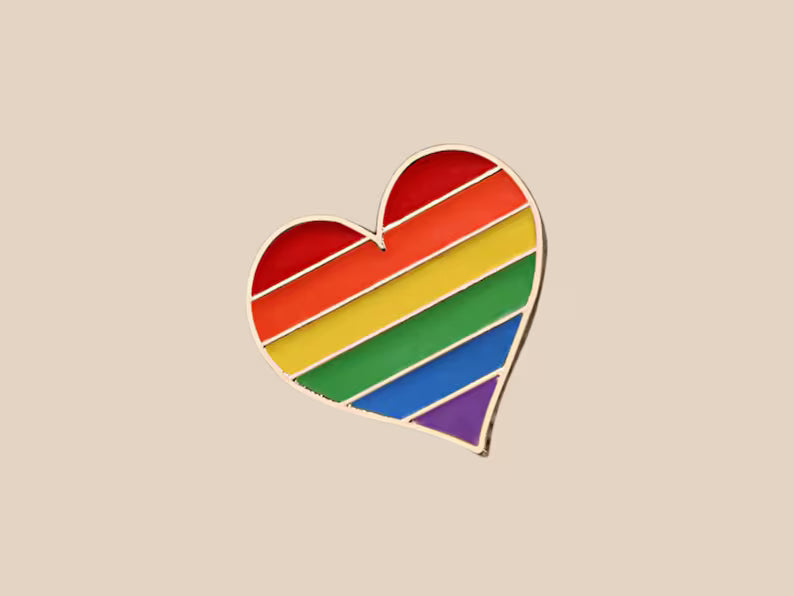 Rainbow heart-shaped pin on a beige background