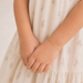 Gold bracelet on a child's wrist with a light background