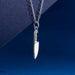 close up detail of sterling silver knife charm on chain on blue background