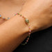 a rainbow tourmaline gold bracelet hangs delicately on a wrist