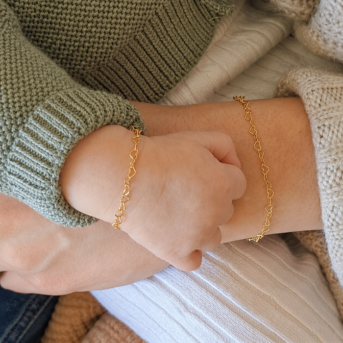 Close-up of a person wearing a gold bracelet with a soft focus background