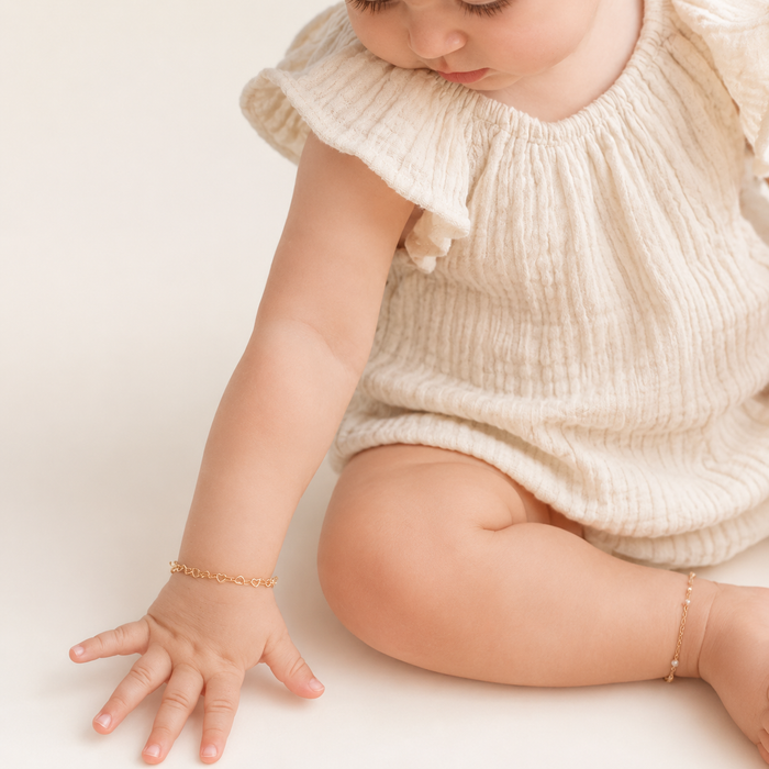 Baby wearing a gold bracelet on a plain background