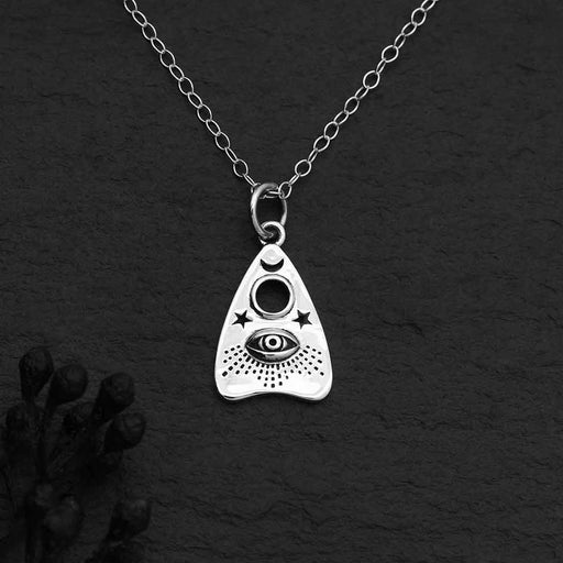 close up detailed view of ouija planchette silver charm with eyeball and stars