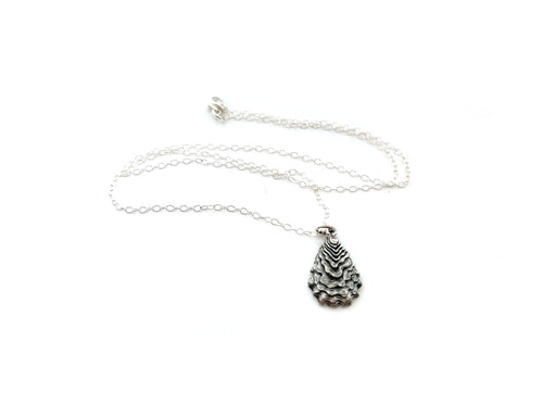 a silver necklace featuring a detailed oyster pendant in silver