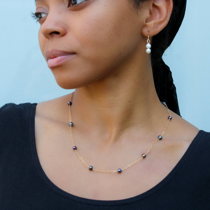 photo of lady in a black blouse wearing a peacock freshwater pearl gold necklace
