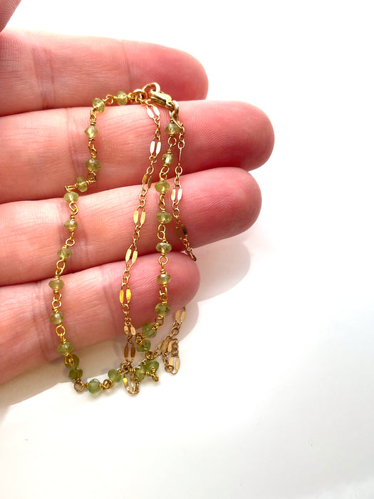 view of a hand holding a peridot handmade bracelet to showcase size