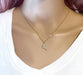 A gold pickleball paddle charm hangs from a delicate gold chain on a model's neck.