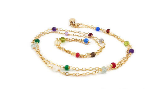 handmade wire wrapped multi gemstone gold necklace laid out in a swirl shape