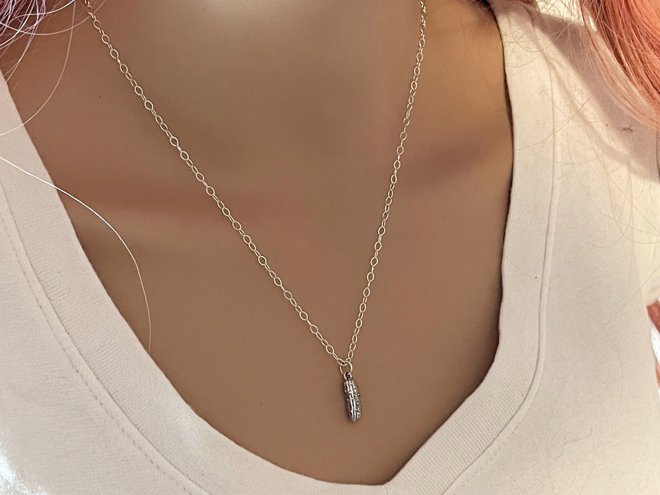 Sterling silver pickle charm necklace on model's neck in white shirt