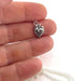 a sterling silver strawberry charm displayed on a few fingers to demonstrate size