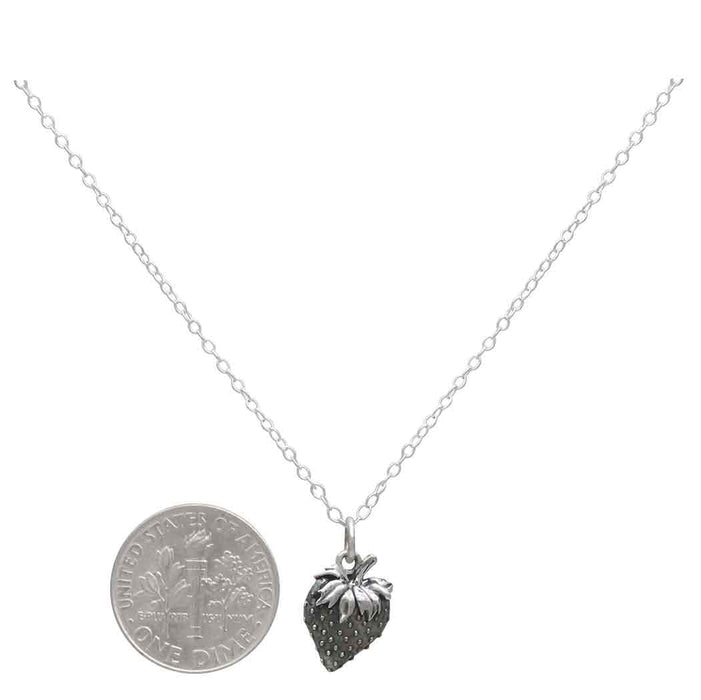 strawberry silver charm hanging on a silver cable chain next to a USD dine to demonstrate size