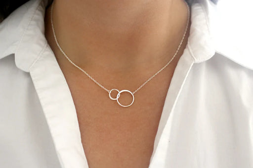 close up view of two silver linked circles necklace on a model