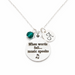 Necklace with a silver pendant featuring 'When words fail... music speaks' and a green bead on a white background