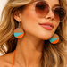 Woman wearing sunglasses and colorful earrings with a neutral background