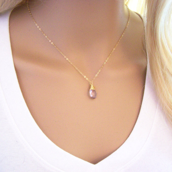 A pink amethyst gemstone wire wrapped briolette teardrop necklace on a gold filled chain, displayed on a mannequin.